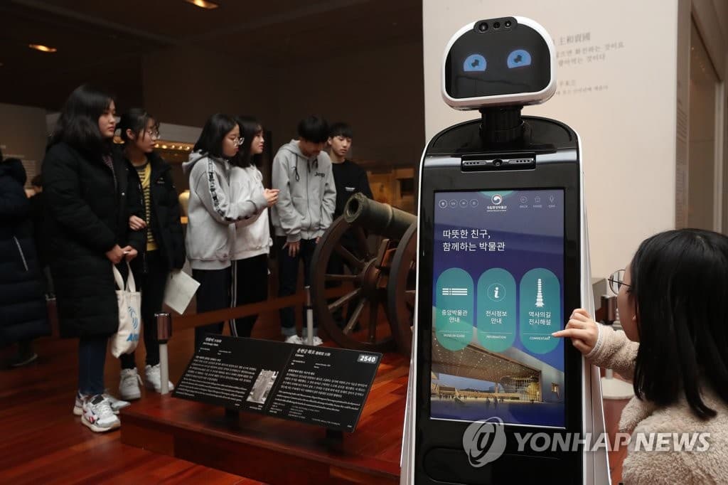 A sleek, wheeled robot with a touchscreen display provides wayfinding assistance in a large museum gallery.